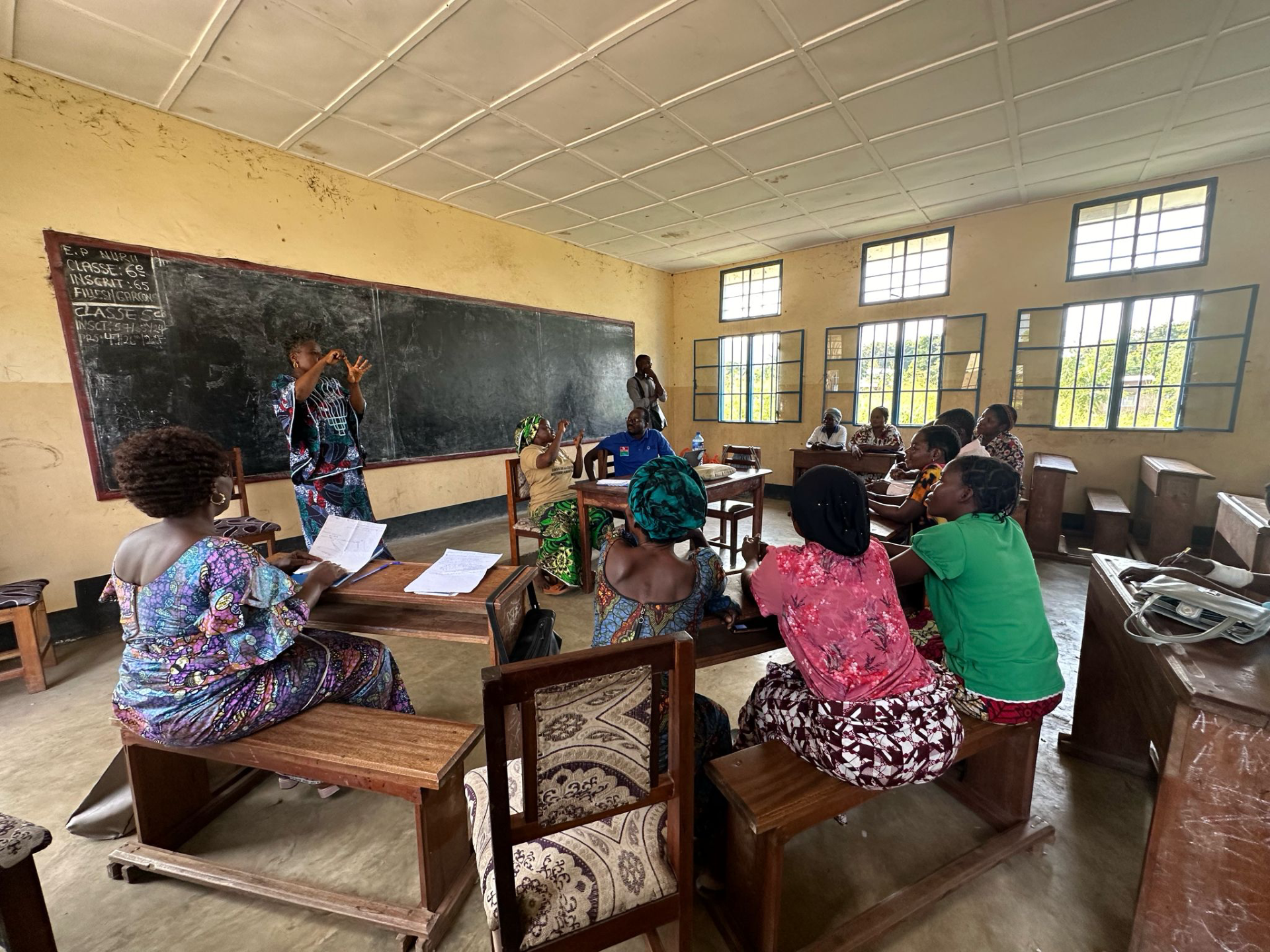 A group of women sitting at desks in a classroom listening to a speaker